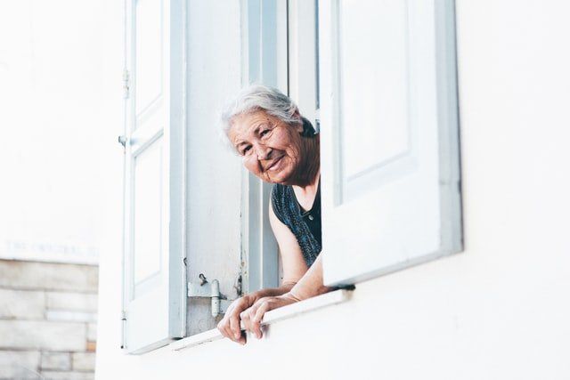 emerytka uśmiechająca się przez okno